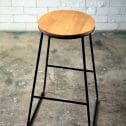 A stylish black wooden top stool featuring a wooden seat and black legs, offered by RSVP Event Hire in Perth.