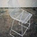 Trendy white wire dining chair with a metal frame and a comfy white cushion, a stylish addition to any decor available from RSVP Event Hire in Perth.