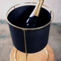 A bottle of champagne elegantly placed in a black and gold wine bucket, supported by a luxurious gold stand, perfect for your next engagement party.