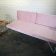 A stylish blush pink couch with metal legs against a white brick wall, perfect for events and available for hire in Perth.
