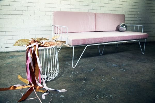 BLUSH PINK COUCH 04_resized Chic blush pink velvet couch with metal legs in front of a white brick wall, perfect for any event and available for hire in Perth.
