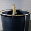 A bottle of champagne nestled in a black bucket, enhanced by a striking gold stand for a touch of luxury, a fantastic addition to your next party event.