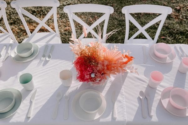 Kids-crossback-chairs-and-tabkes-Kids-party-hire Elegant table with white chairs adorned with pink flowers, designed for Little One's events by RSVP Event Hire in Perth.